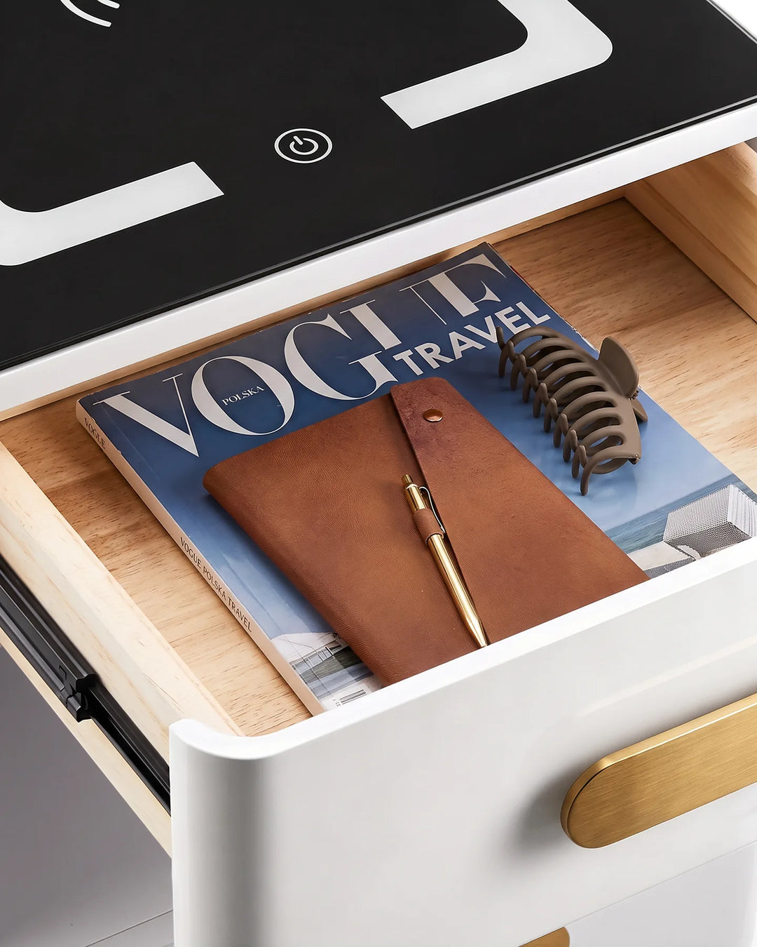 Top view of an open drawer in the Clara bedside table containing a magazine and notebook, showcasing storage space.