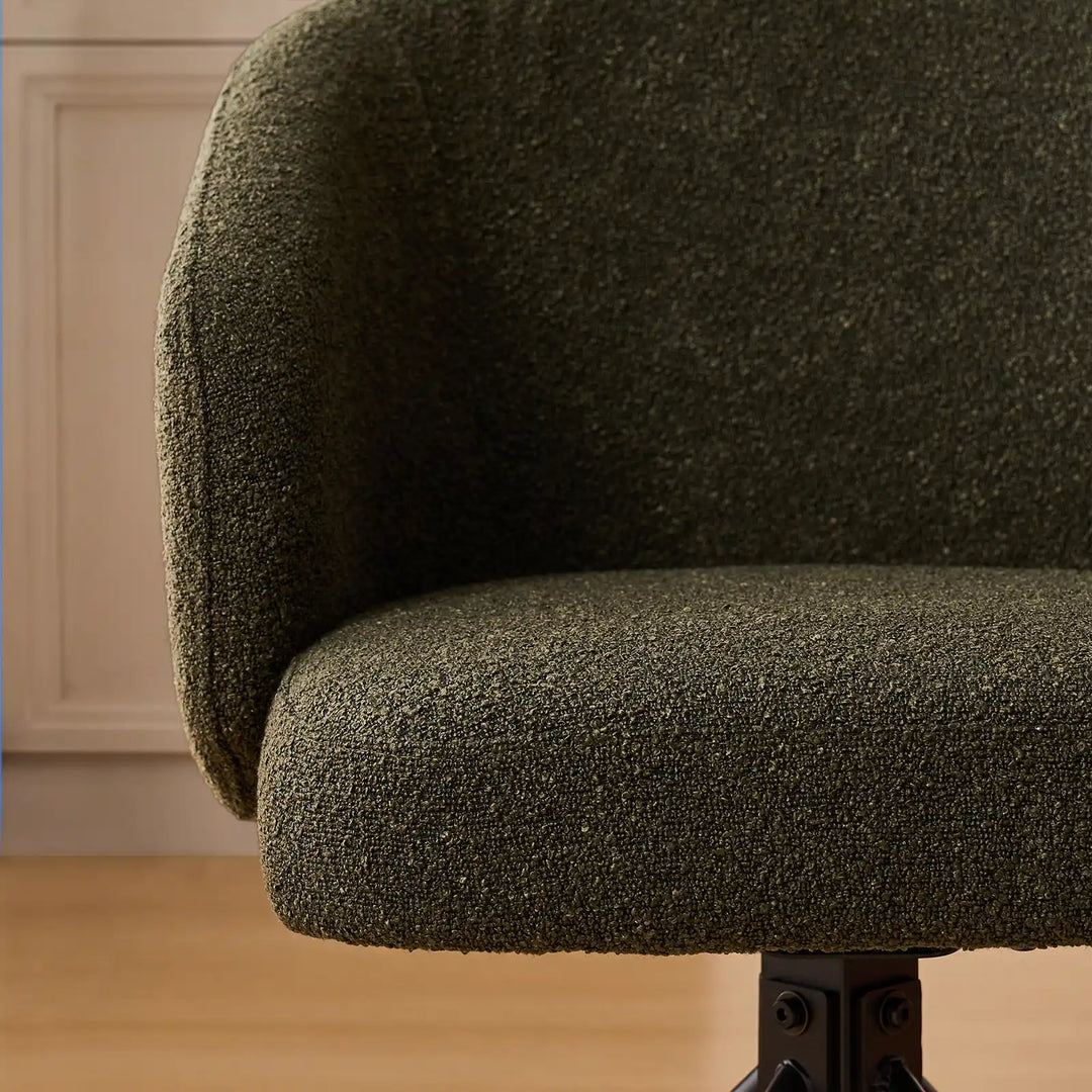 Close-up of the Cleo swivel chair's curved padded armrest and deep seat cushion, showcasing the cosy looped texture of the moss green bouclé upholstery.