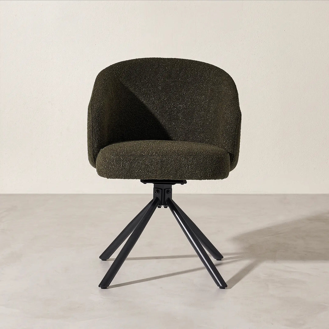 Front studio view of the Cleo green bouclé swivel chair, showcasing the supportive padded seat cushion and splayed four-star black metal swivel base.