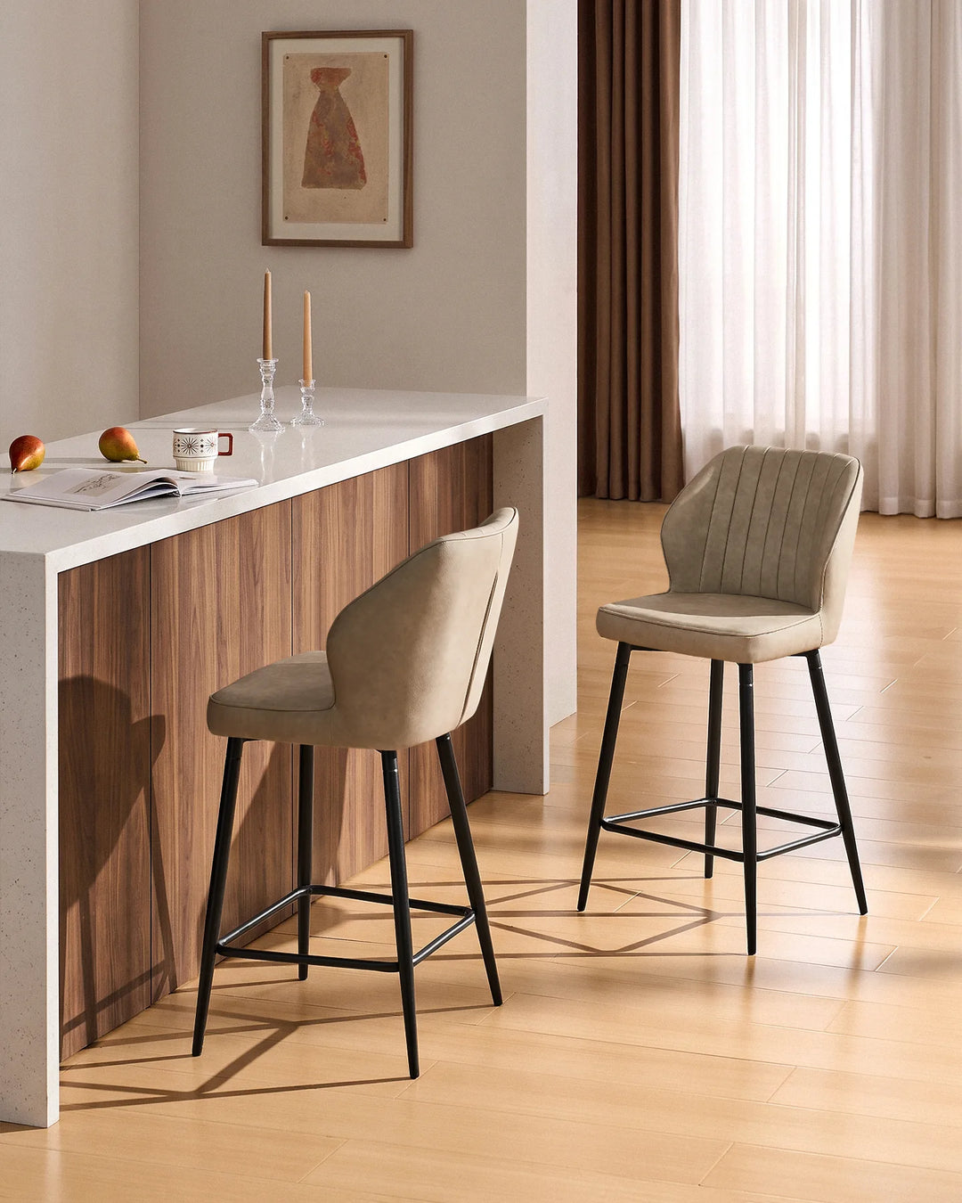 Danforth beige bar stools with padded vertical channel detailing and black metal legs positioned at a modern kitchen island