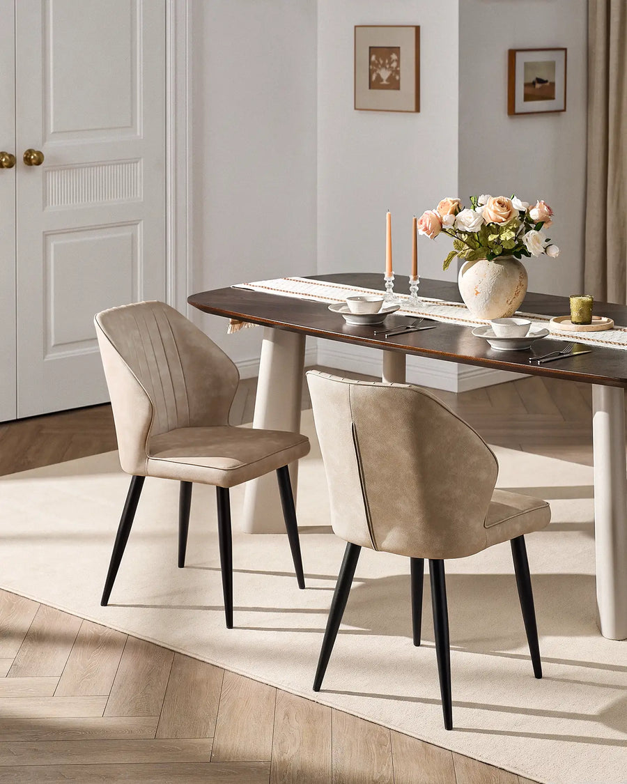 Pair of Danforth beige faux leather dining chairs styled with a modern wooden dining table.