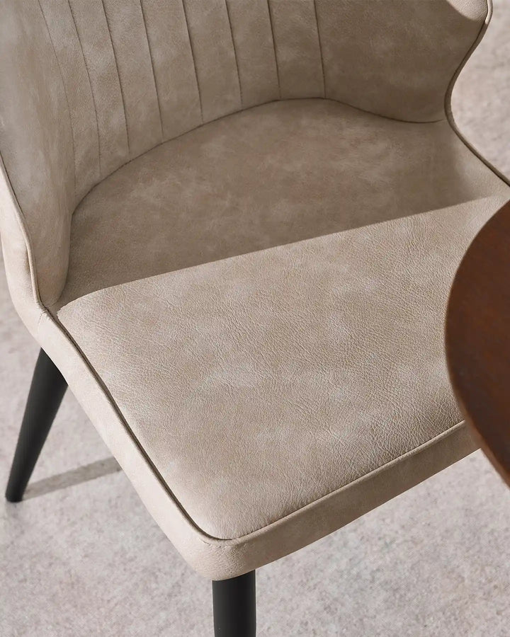 Detail shot of the durable beige faux leather and high-density foam seat of the Danforth chair.