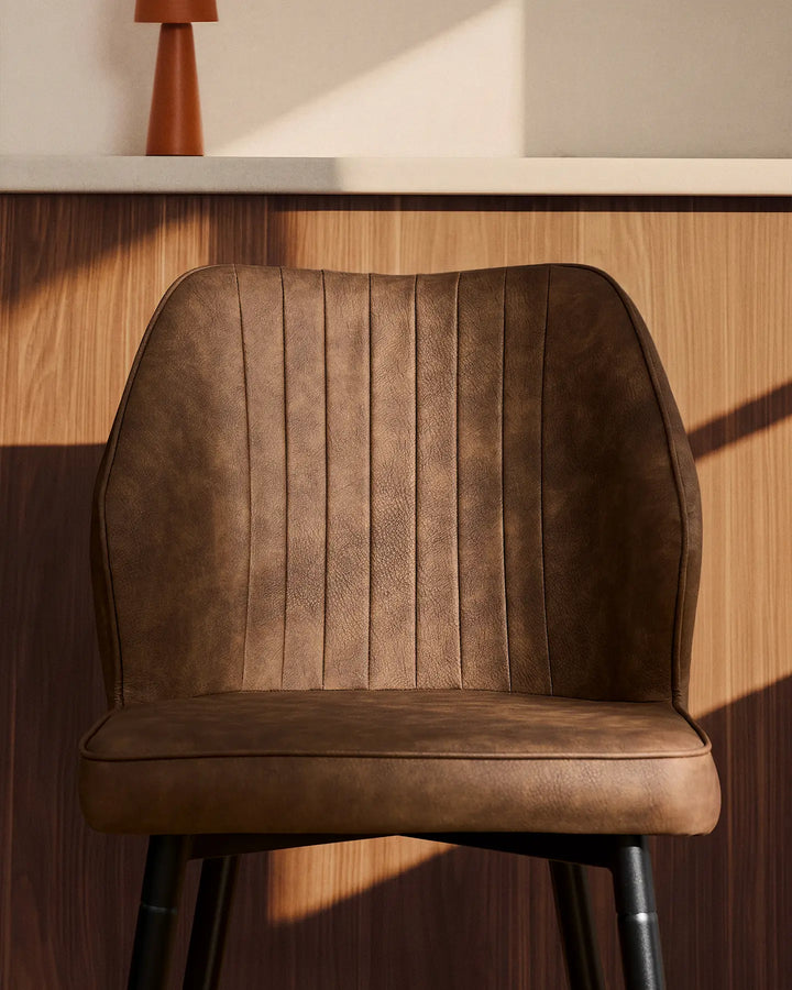 Side view close-up of a Danforth Brown bar stool highlighting the vertical stitched detailing and cushioned seat
