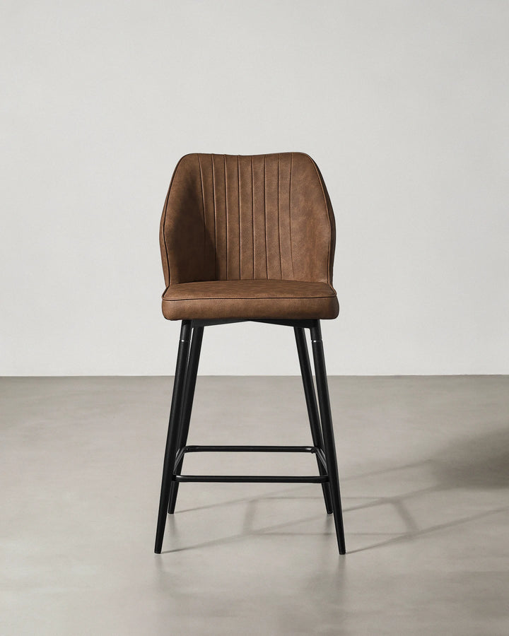 Front view of a Danforth Brown bar stool with a curved padded backrest, upholstered seat and slim black metal legs