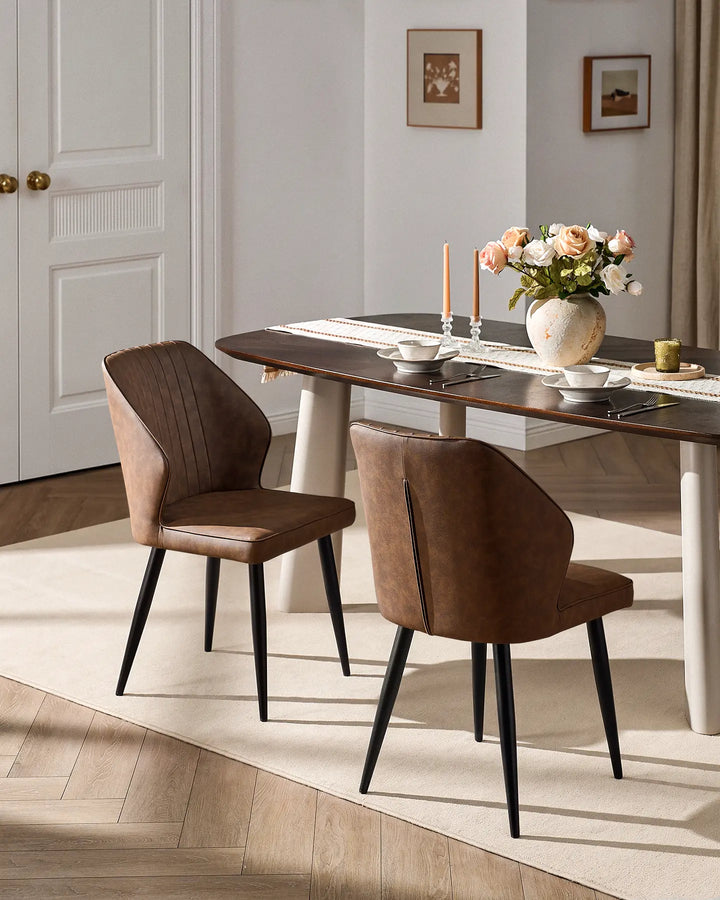 Pair of Danforth brown faux leather dining chairs styled with a modern wooden dining table.