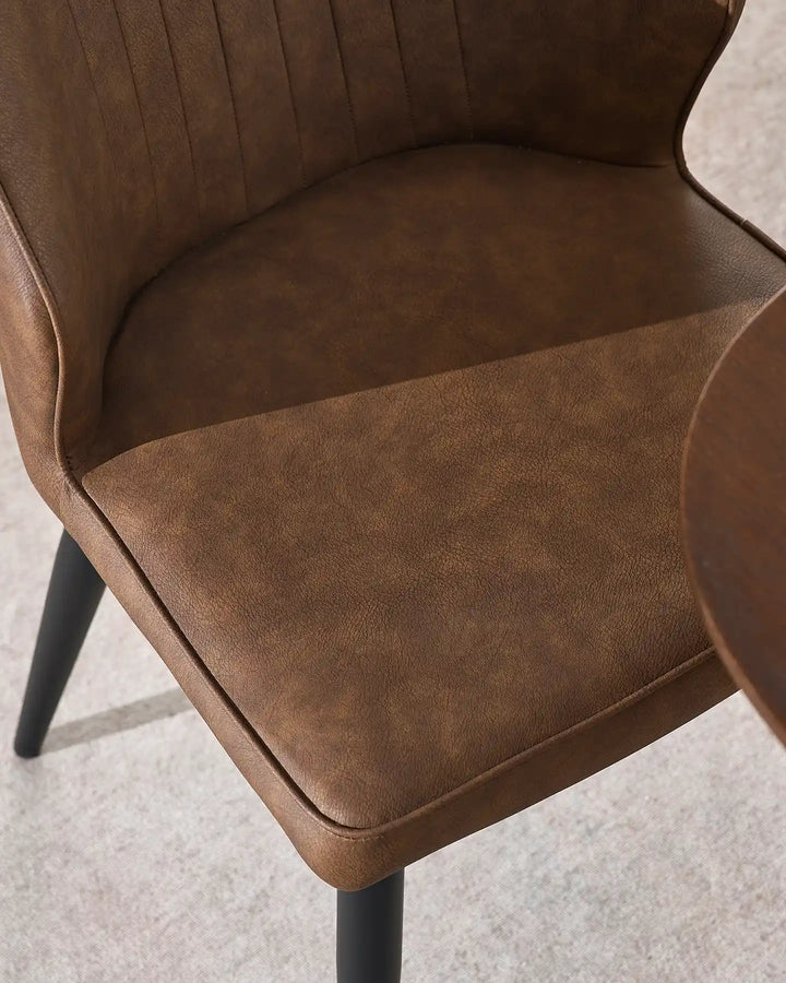 Detail shot of the durable brown faux leather and high-density foam seat of the Danforth chair.