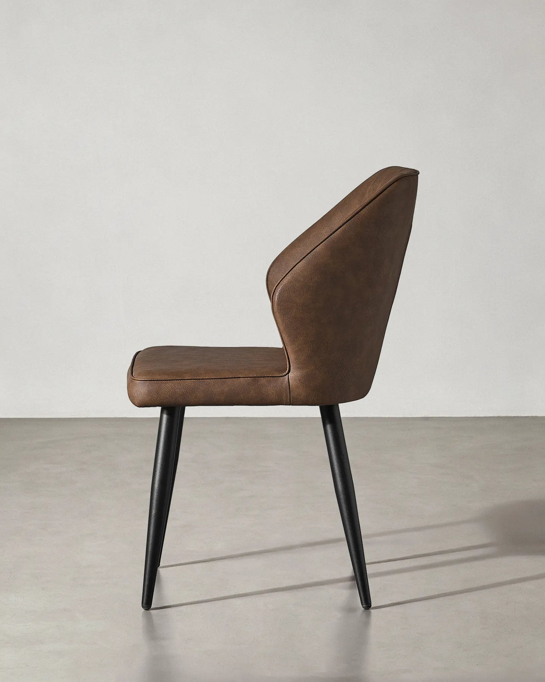 Side profile of the Danforth chair showing the reclined backrest and sturdy black metal legs.