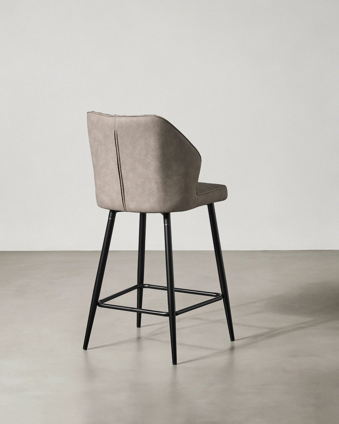 Rear view of a Danforth Light Grey bar stool showing the upholstered backrest, curved silhouette and black metal frame