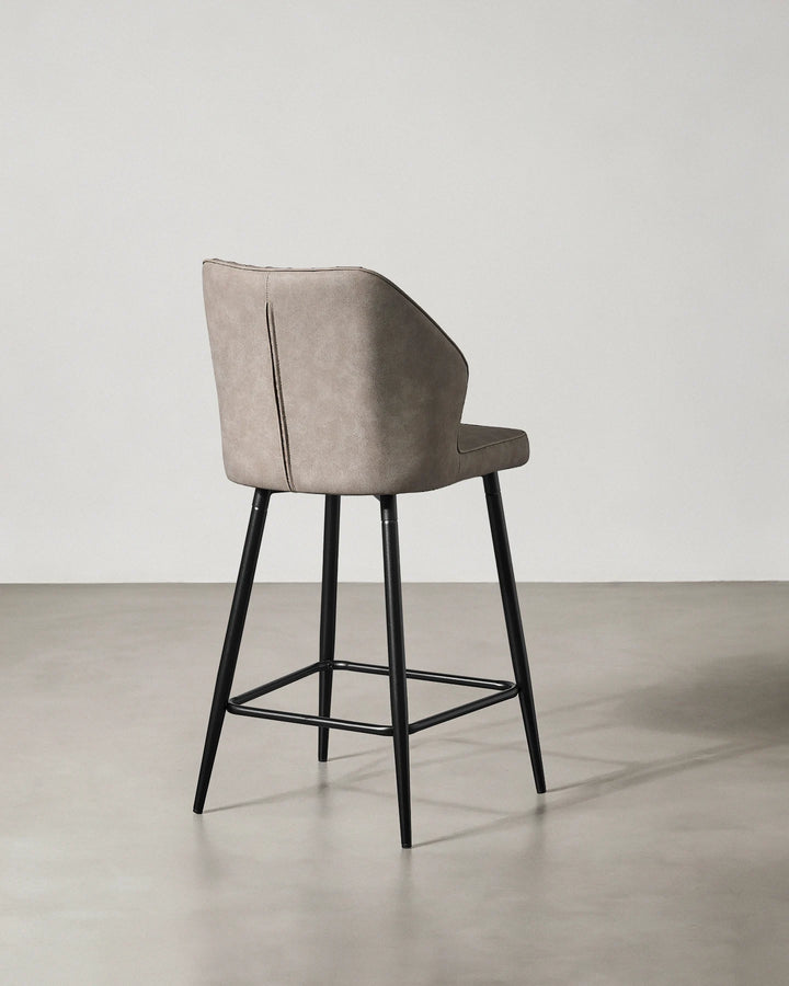 Rear view of a Danforth Light Grey bar stool showing the upholstered backrest, curved silhouette and black metal frame