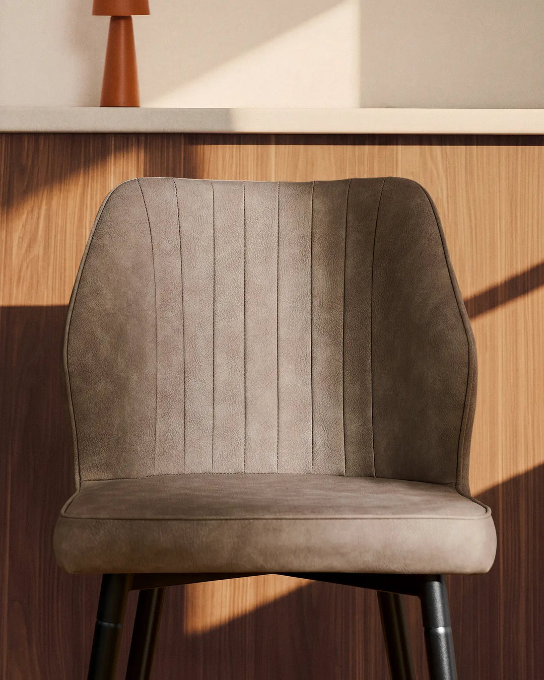 Side view close-up of a Danforth Light Grey bar stool highlighting the vertical stitched detailing and cushioned seat