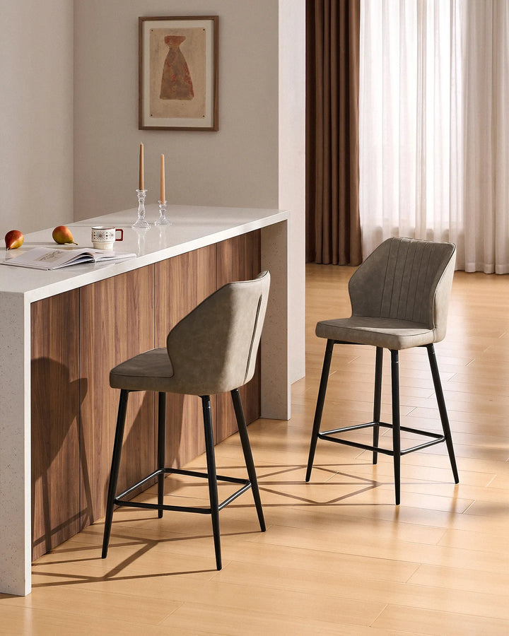 Danforth Light Grey bar stools with padded vertical channel detailing and black metal legs positioned at a modern kitchen island