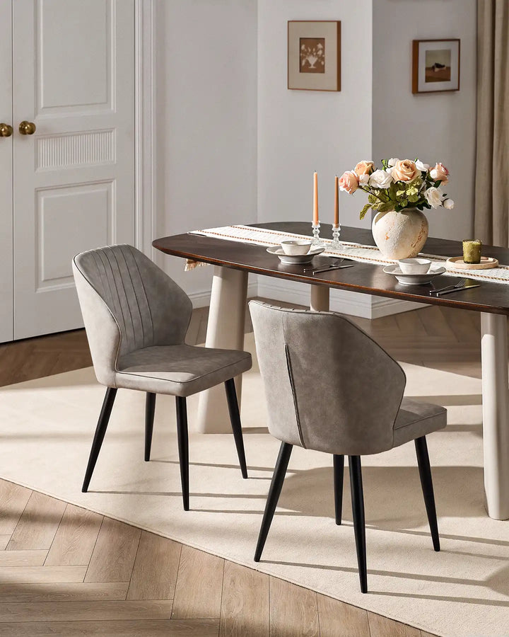 Pair of Danforth light grey faux leather dining chairs styled with a modern wooden dining table.
