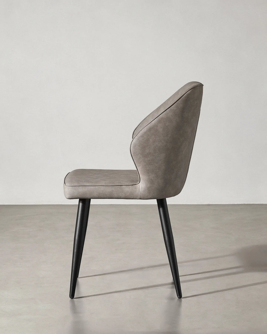 Side profile of the Danforth chair showing the reclined backrest and sturdy black metal legs.