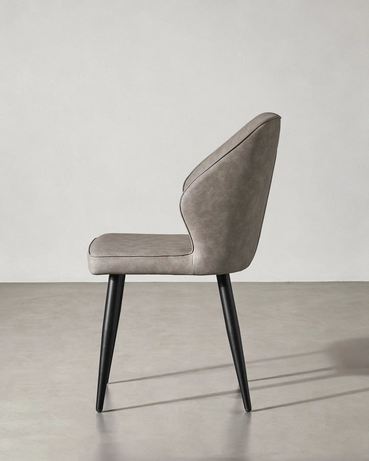 Side profile of the Danforth chair showing the reclined backrest and sturdy black metal legs.