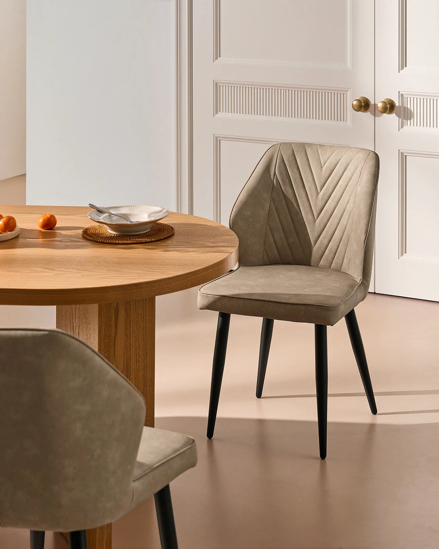 Beige faux leather dining chair beside a wooden dining table, styled with neutral interiors and classic wall panelling.