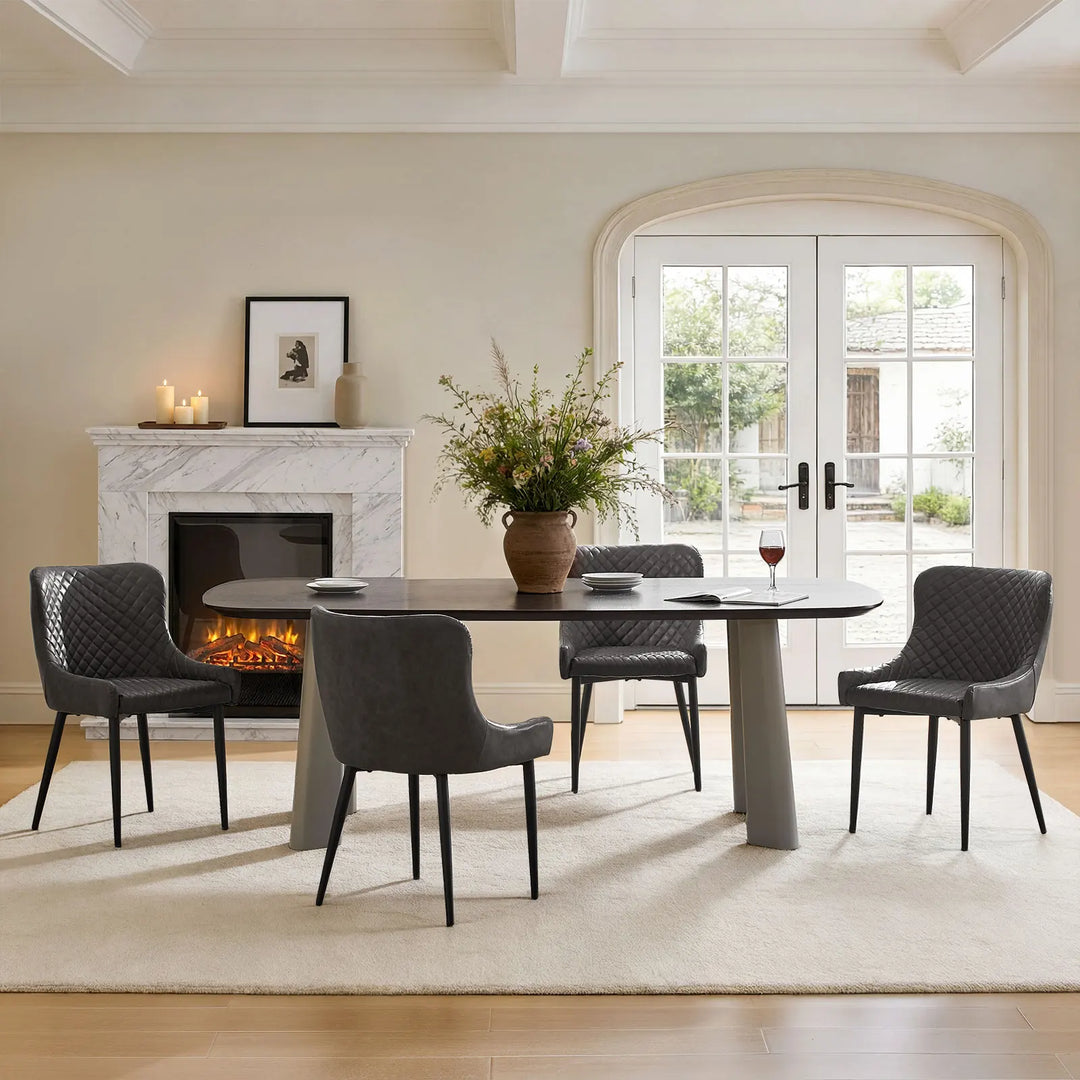 Four grey faux leather dining chairs arranged around a dining table in a modern dining room
