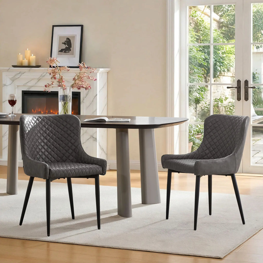 Pair of grey faux leather dining chairs styled next to a dining table in a contemporary dining space
