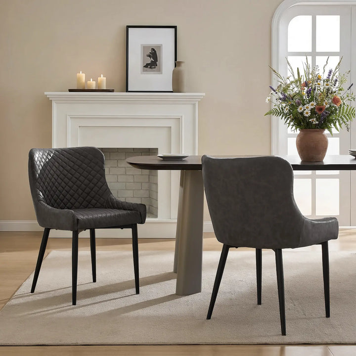 Two grey faux leather dining chairs beside a dining table in a modern dining room
