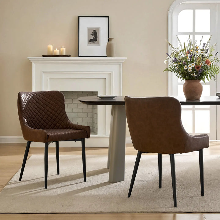 Two brown faux leather dining chairs beside a dining table in a modern dining room