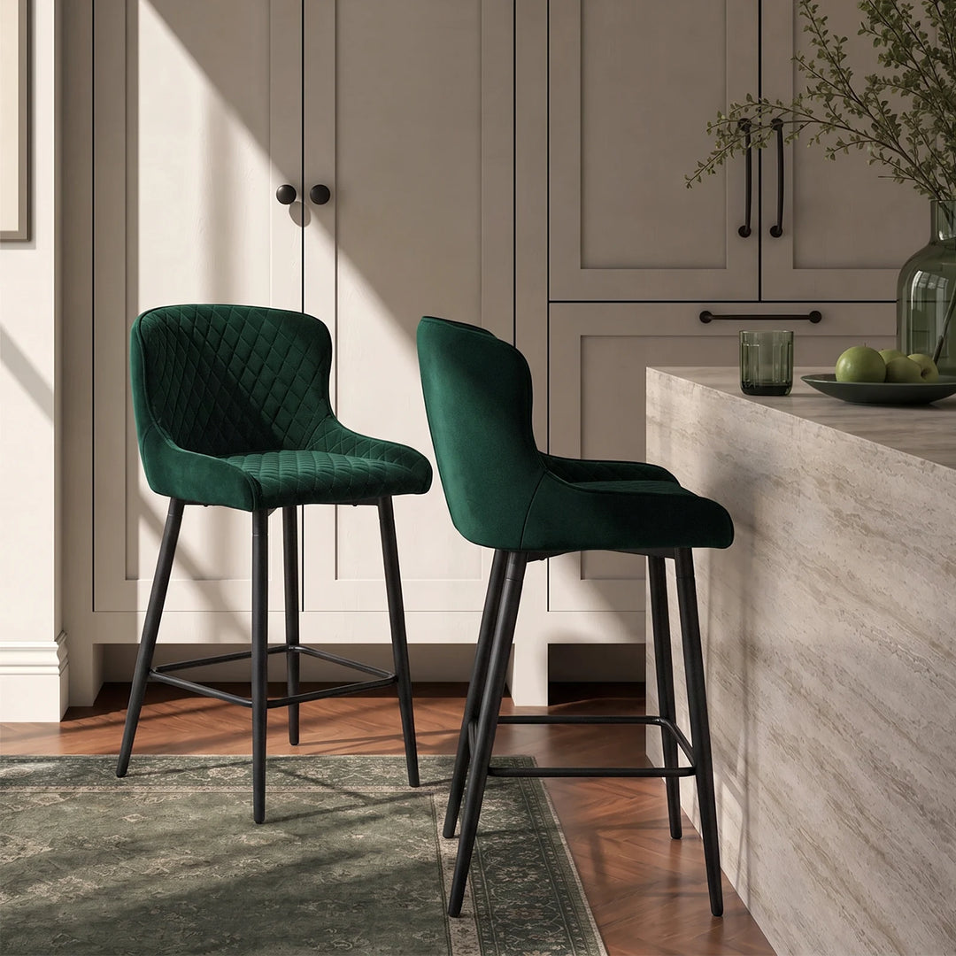 Pair of Dundas green velvet bar stools positioned at a kitchen island, showcasing their curved upholstered backs