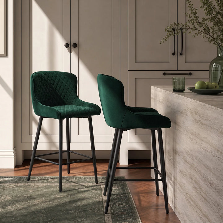 Pair of Dundas green velvet bar stools positioned at a kitchen island, showcasing their curved upholstered backs