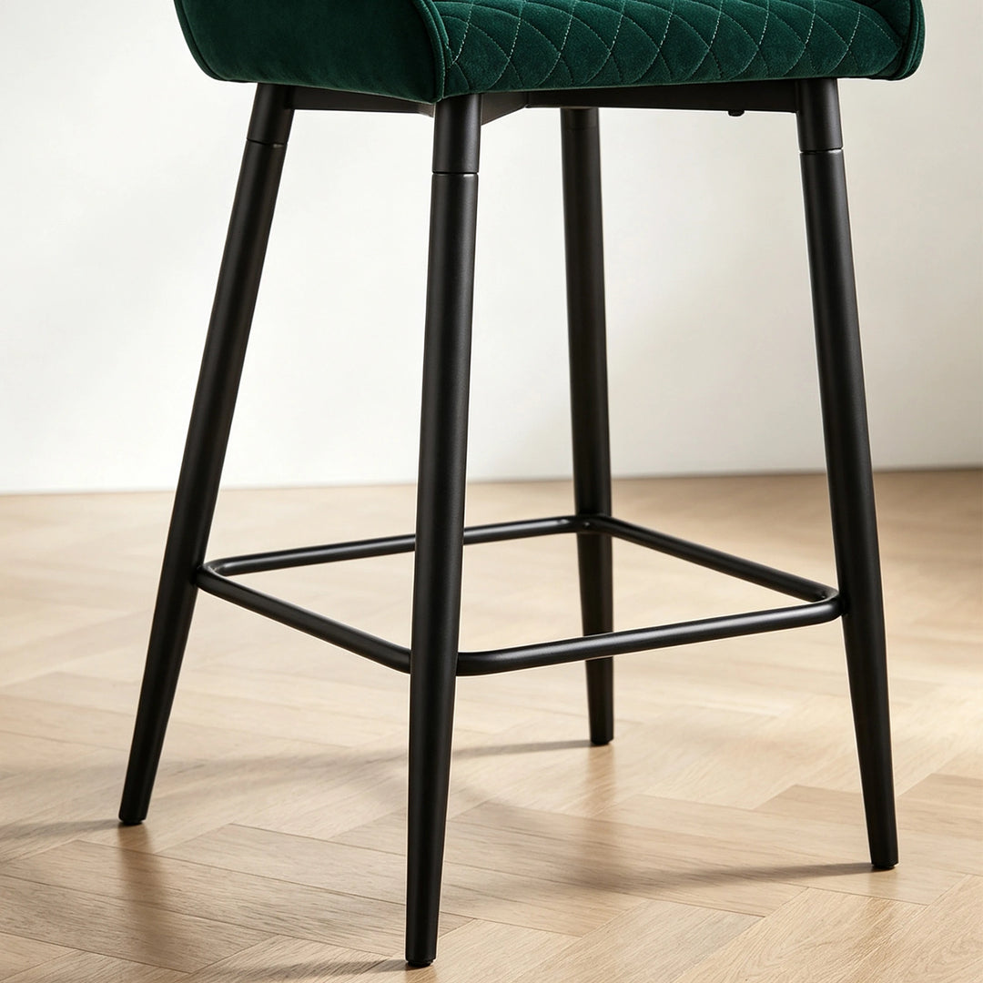 Close-up of Dundas green velvet bar stool showing the black metal legs and integrated footrest