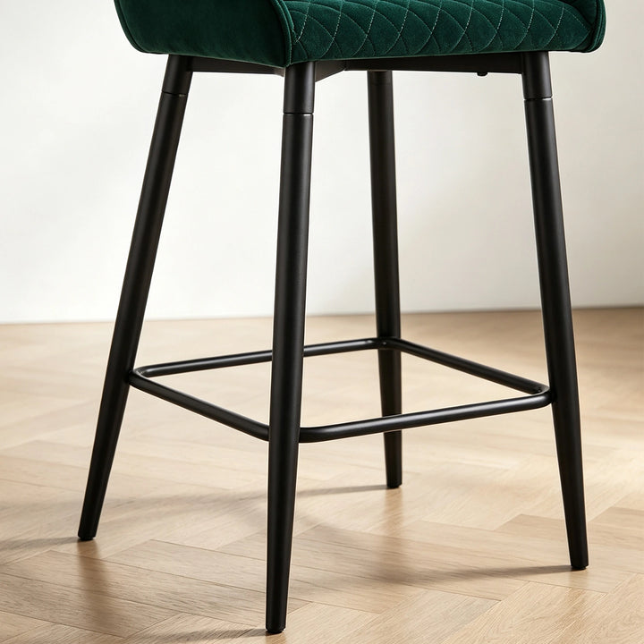 Close-up of Dundas green velvet bar stool showing the black metal legs and integrated footrest