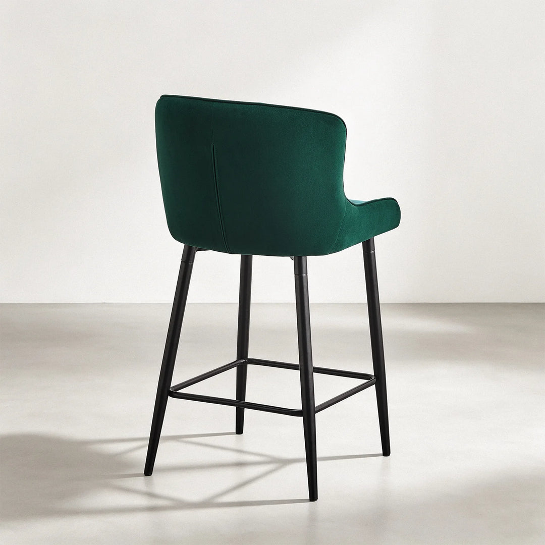 Rear view of Dundas green velvet bar stool showing the curved upholstered back and black metal frame