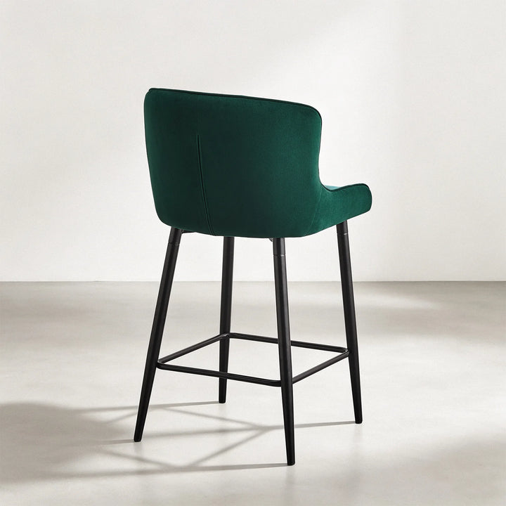Rear view of Dundas green velvet bar stool showing the curved upholstered back and black metal frame