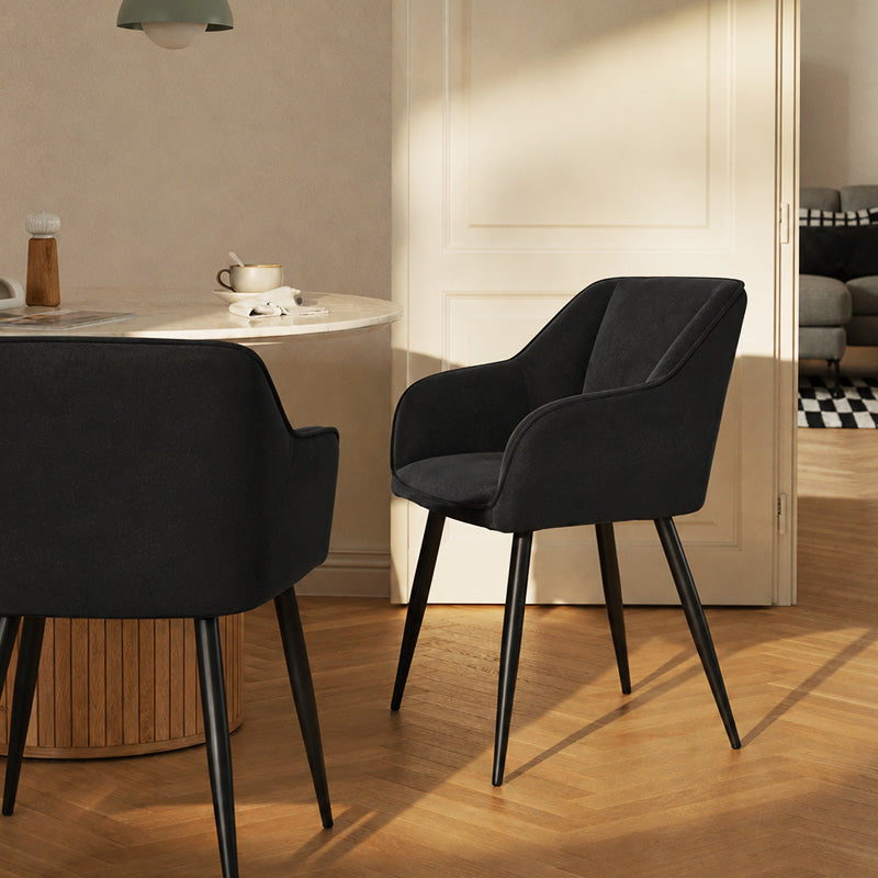Earven Black Velvet Dining Chairs in the dining area, featuring armrests and black metal legs
