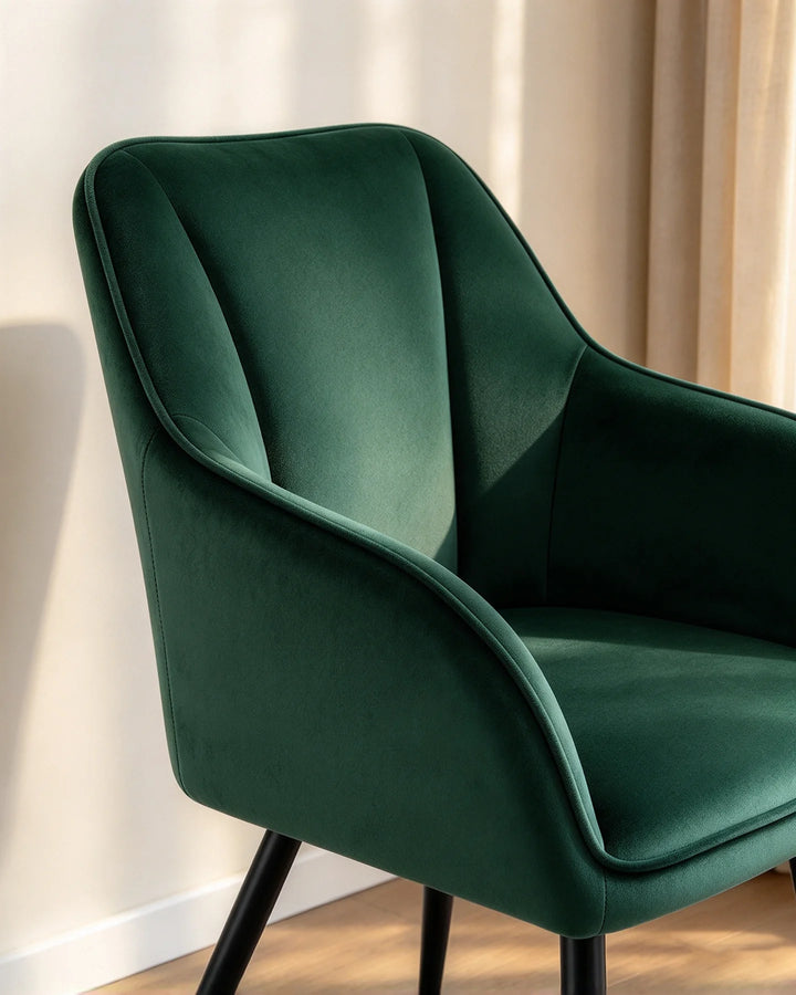 Close-up of the Earven green velvet dining chair highlighting its sculpted curved backrest, padded armrest and soft upholstered finish
