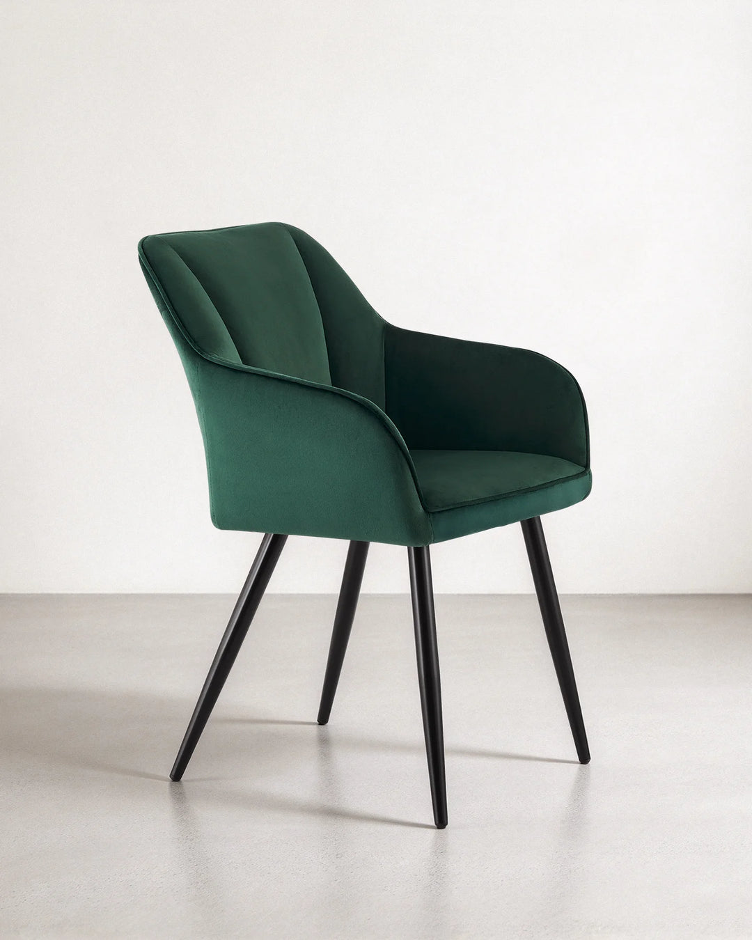 Side profile of the Earven green velvet dining chair highlighting its wraparound backrest, supportive armrests, cushioned seat and slim black legs