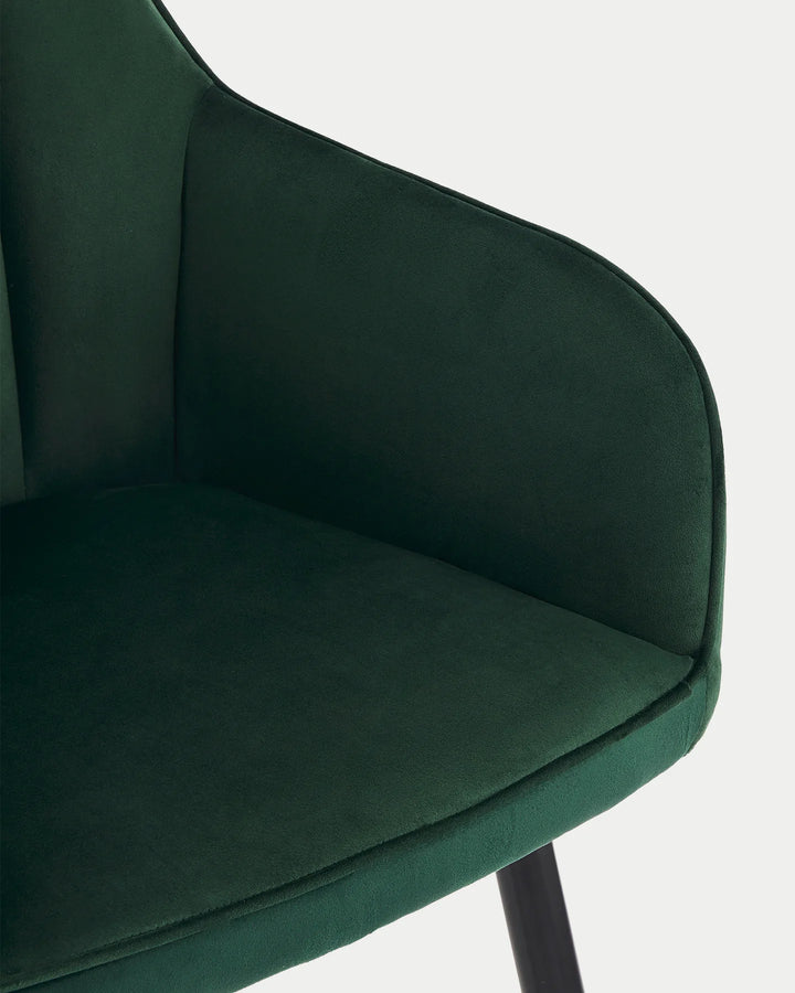 Close-up of the Earven green velvet dining chair showing the soft upholstery, curved backrest and neatly finished seat edge