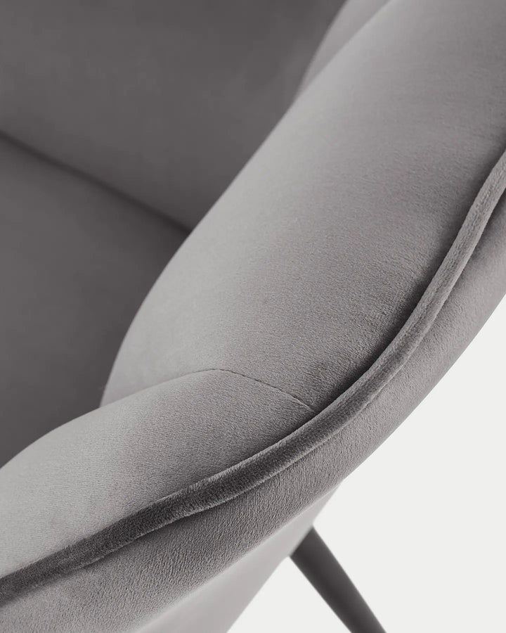 Detailed view of the Earven grey velvet dining chair highlighting the upholstered armrest, smooth fabric finish and neat edge stitching