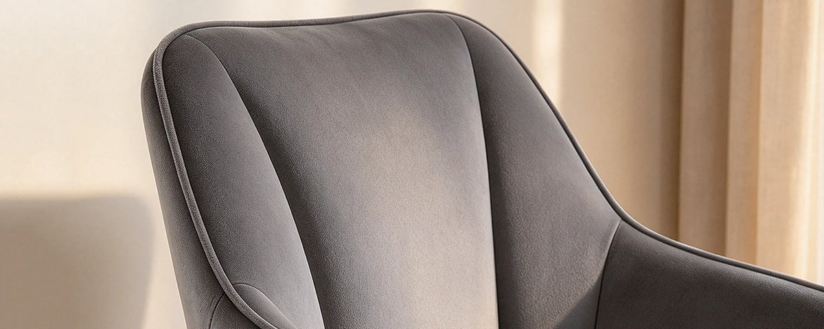 Close-up of the Earven grey velvet dining chair showing the soft upholstery, curved backrest and neatly finished seat edge