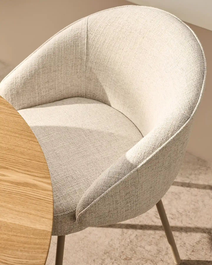 Close-up of the Elowen beige linen dining chair showing thick padded seat cushion and gently curved upholstered armrests