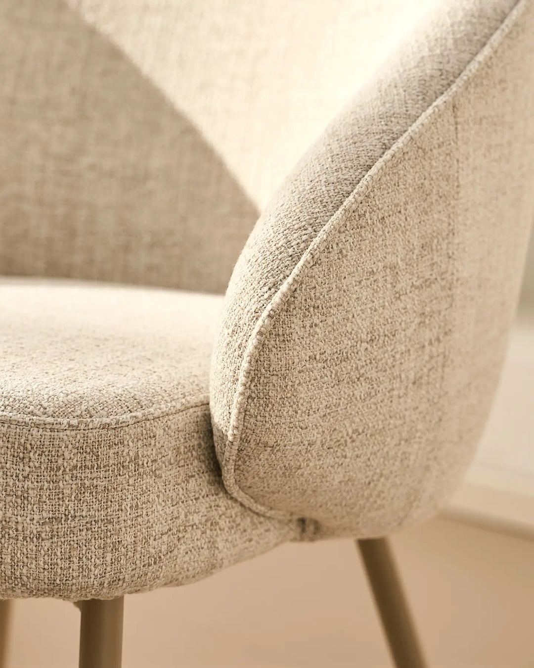 Close-up of the smooth curved armrest design on the Elowen beige linen dining chair with soft upholstery