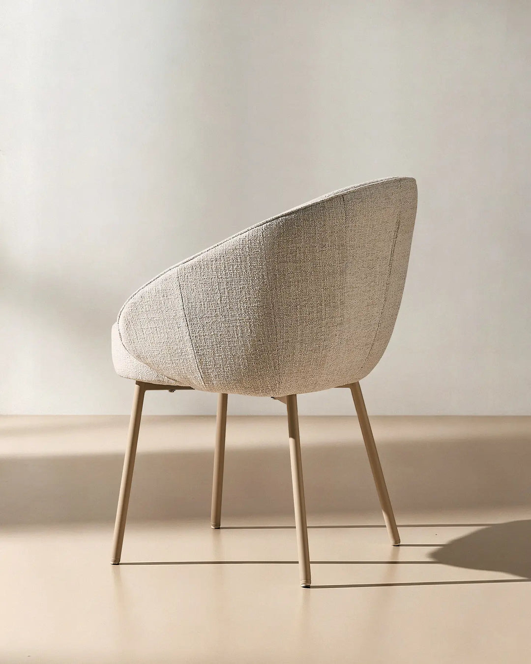 Rear angled view of the Elowen beige linen dining chair showcasing the curved backrest and modern silhouette