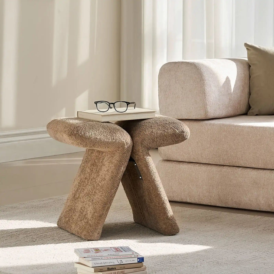 Faye Teddy Brown Accent Stool styled beside a sofa in a modern living room, used as a side stool with books and glasses