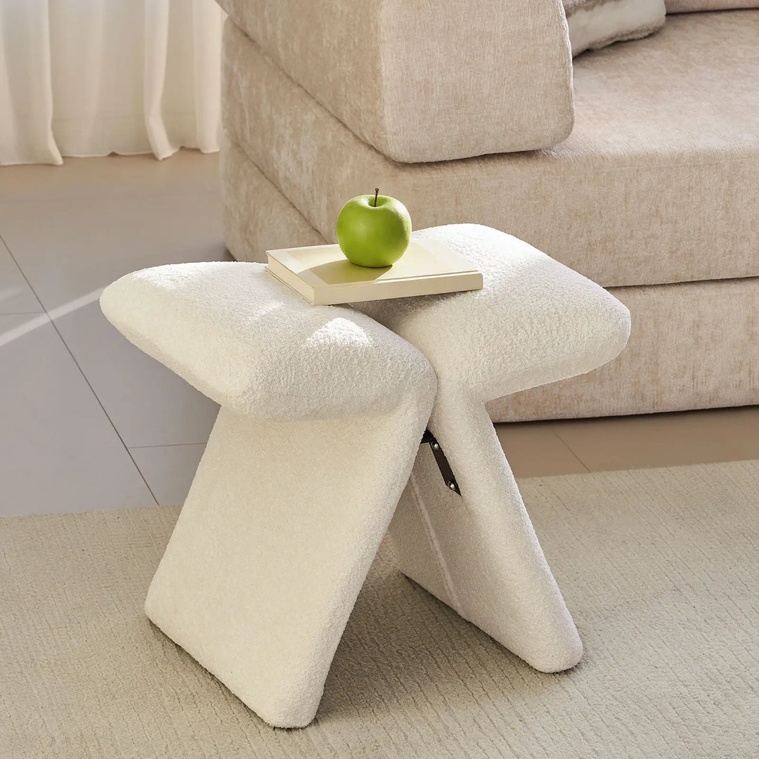Faye warm white Accent Stool styled beside a sofa in a modern living room, serving as a practical side accent.
