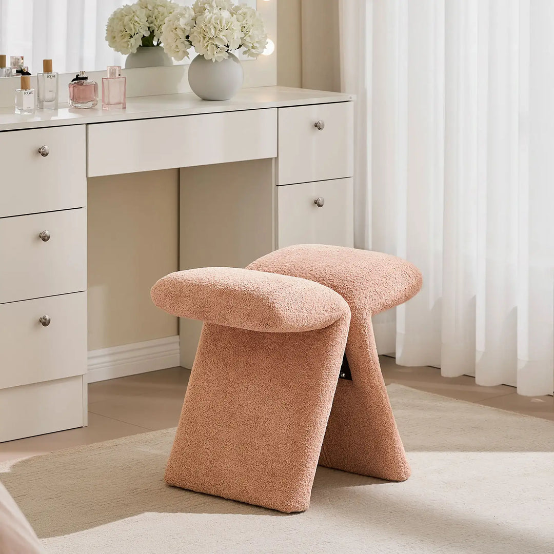 Faye Warm Blush Accent Stool styled as a bedroom vanity stool in front of a white dressing table