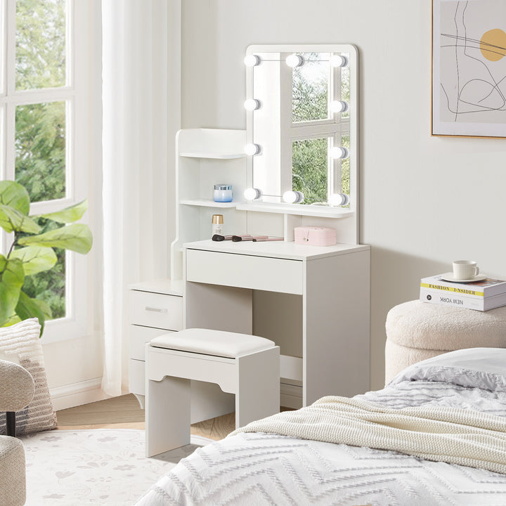 The side view of the white dressing table set, with a mirror and 10 LED bulbs, a 3-drawer cabinet, a big drawer under the tabletop, several shelves, and a stool, in a bright bedroom.