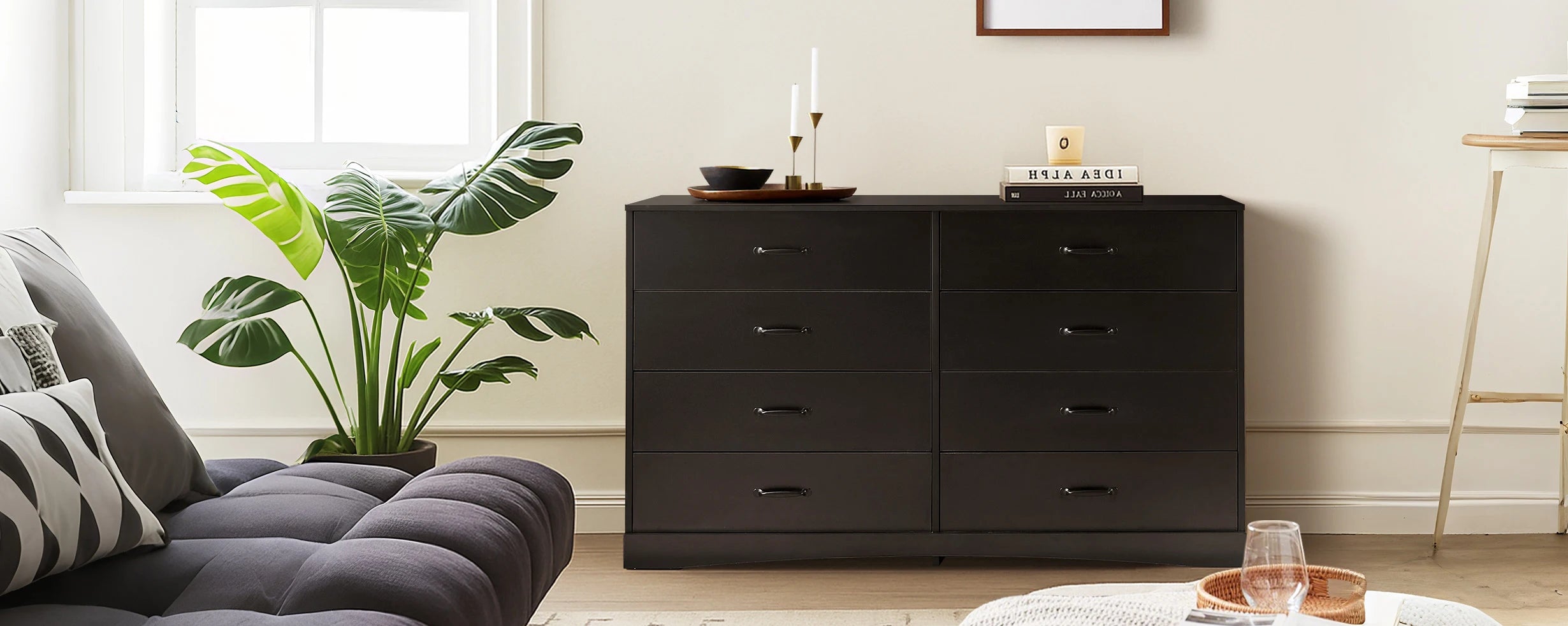 Kamai black 8-drawer chest in airy living room with sofa and plants, by window, styled with decorative items.