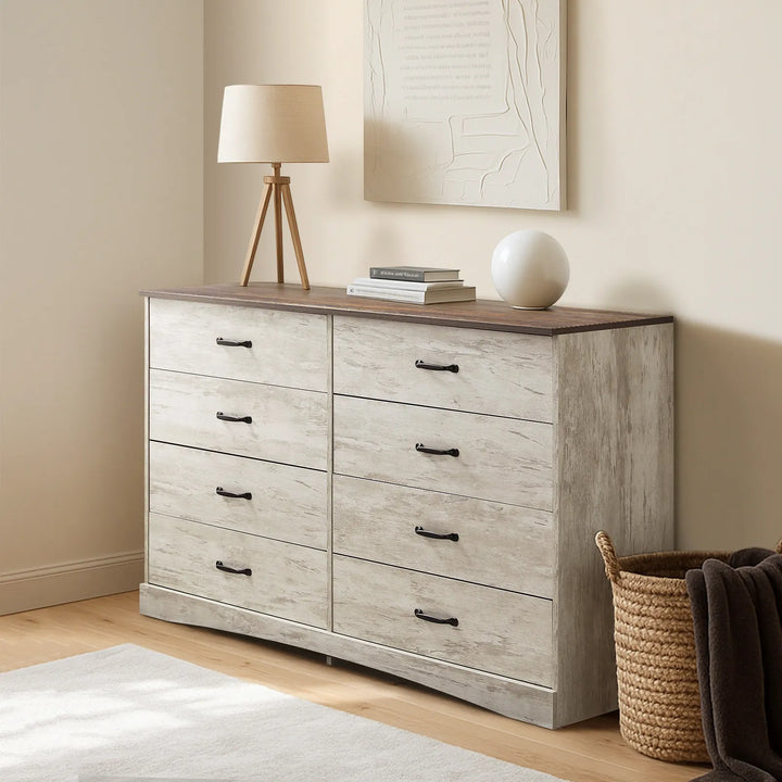 Kamai grey chest of drawers in warm bedroom, top surface with table lamp and stacked books.