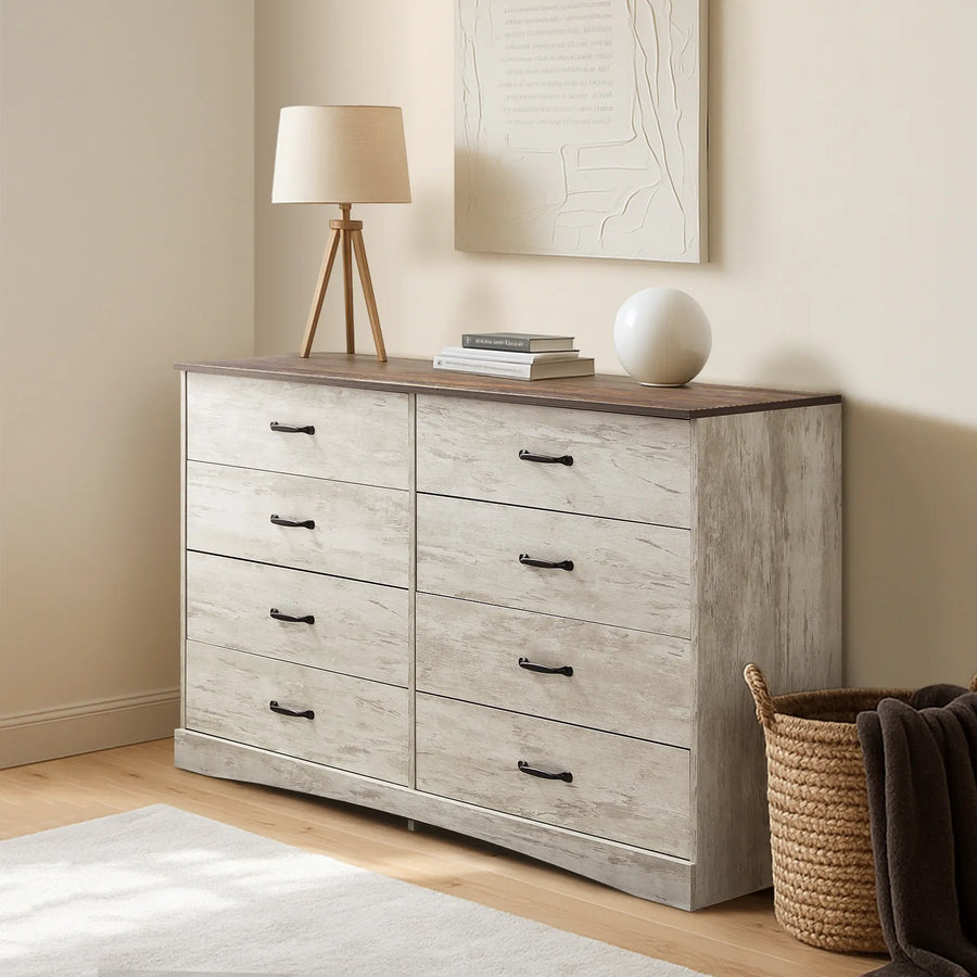 Kamai grey chest of drawers in warm bedroom, top surface with table lamp and stacked books.