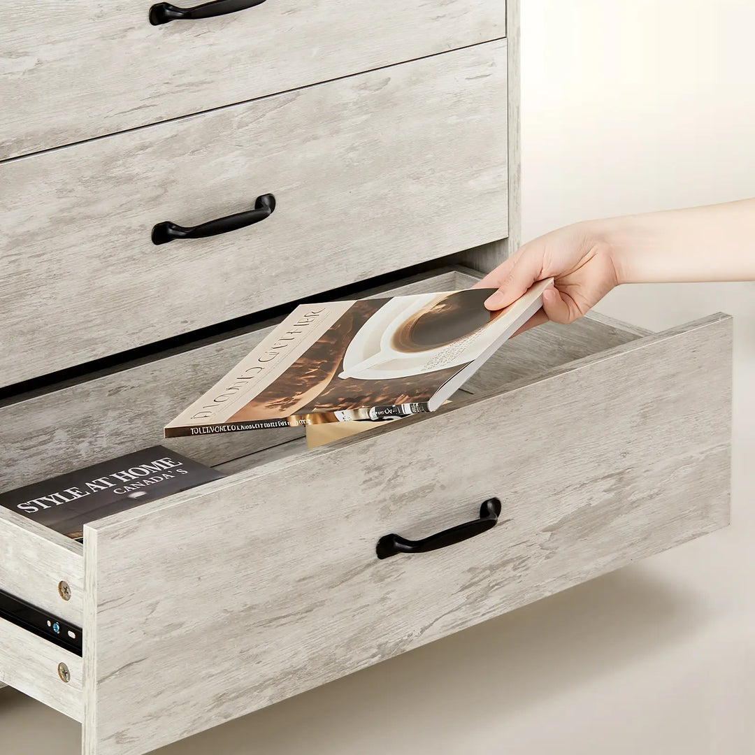 Kamai Grey Chest of Drawer, with large storage drawers, shows a hand putting books in the drawer