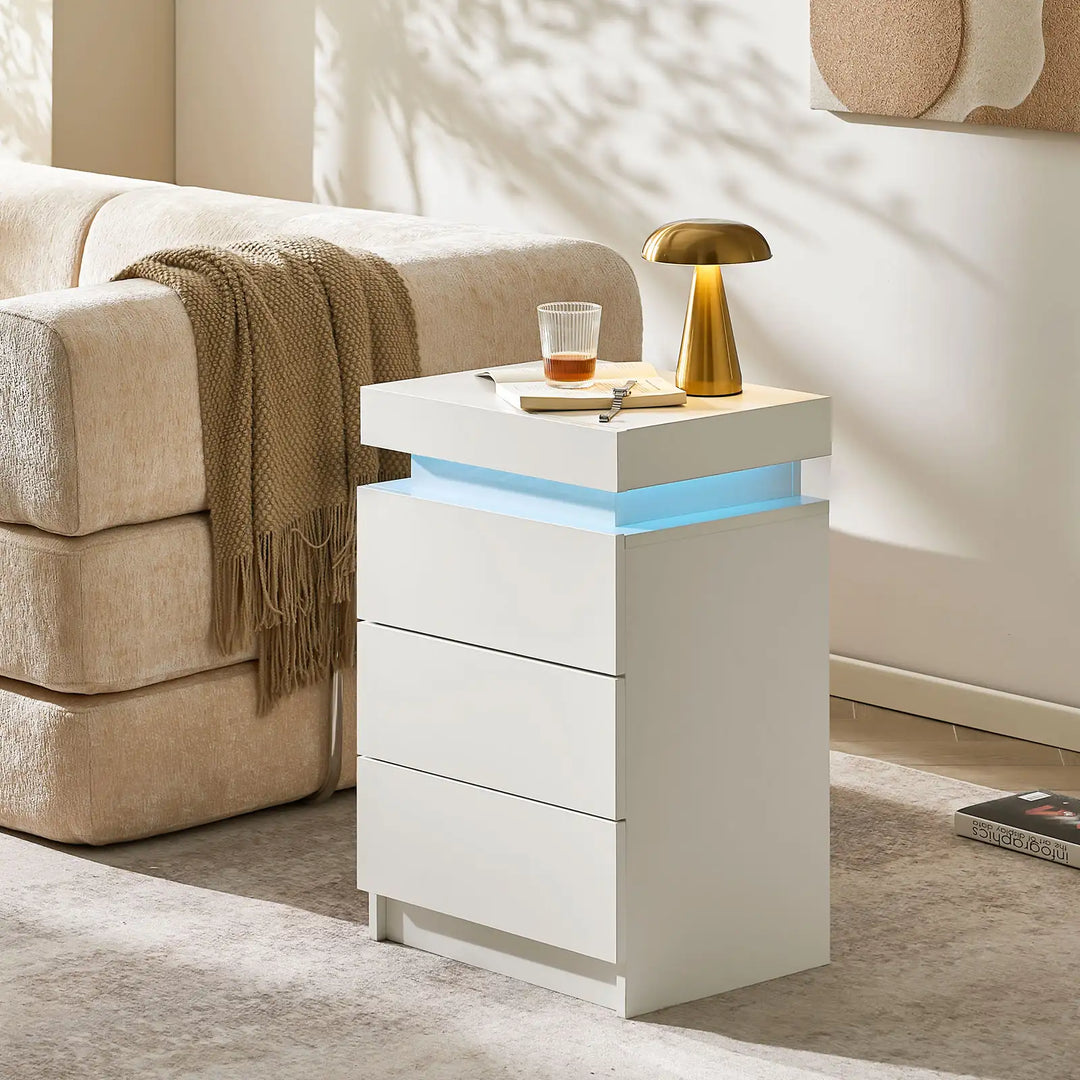 The view of the Kumar Bedside Table near the sofa, serve as a side table, featuring 3 drawers, in a bright room.