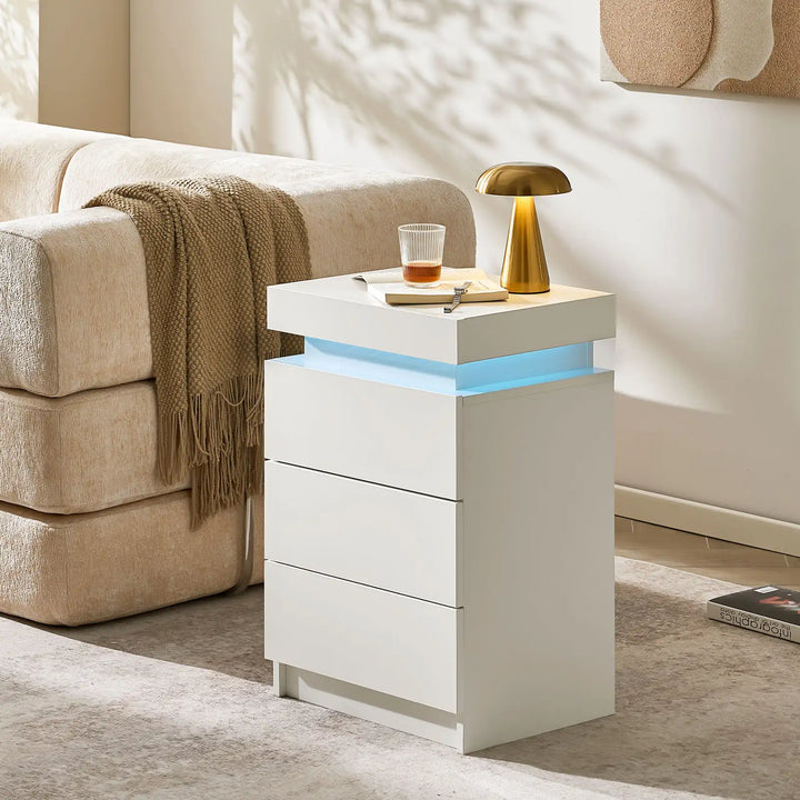 The view of the Kumar Bedside Table near the sofa, serve as a side table, featuring 3 drawers, in a bright room.