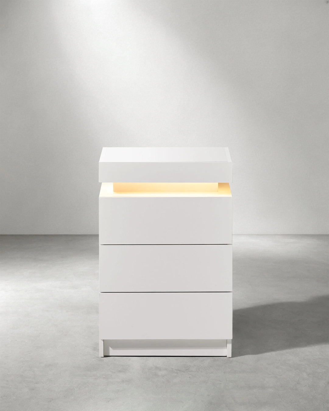 Front view of white Kumar LED bedside table with three drawers and integrated ambient lighting