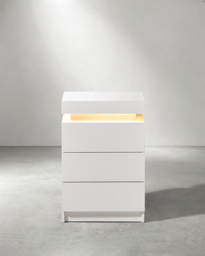 Front view of white Kumar LED bedside table with three drawers and integrated ambient lighting